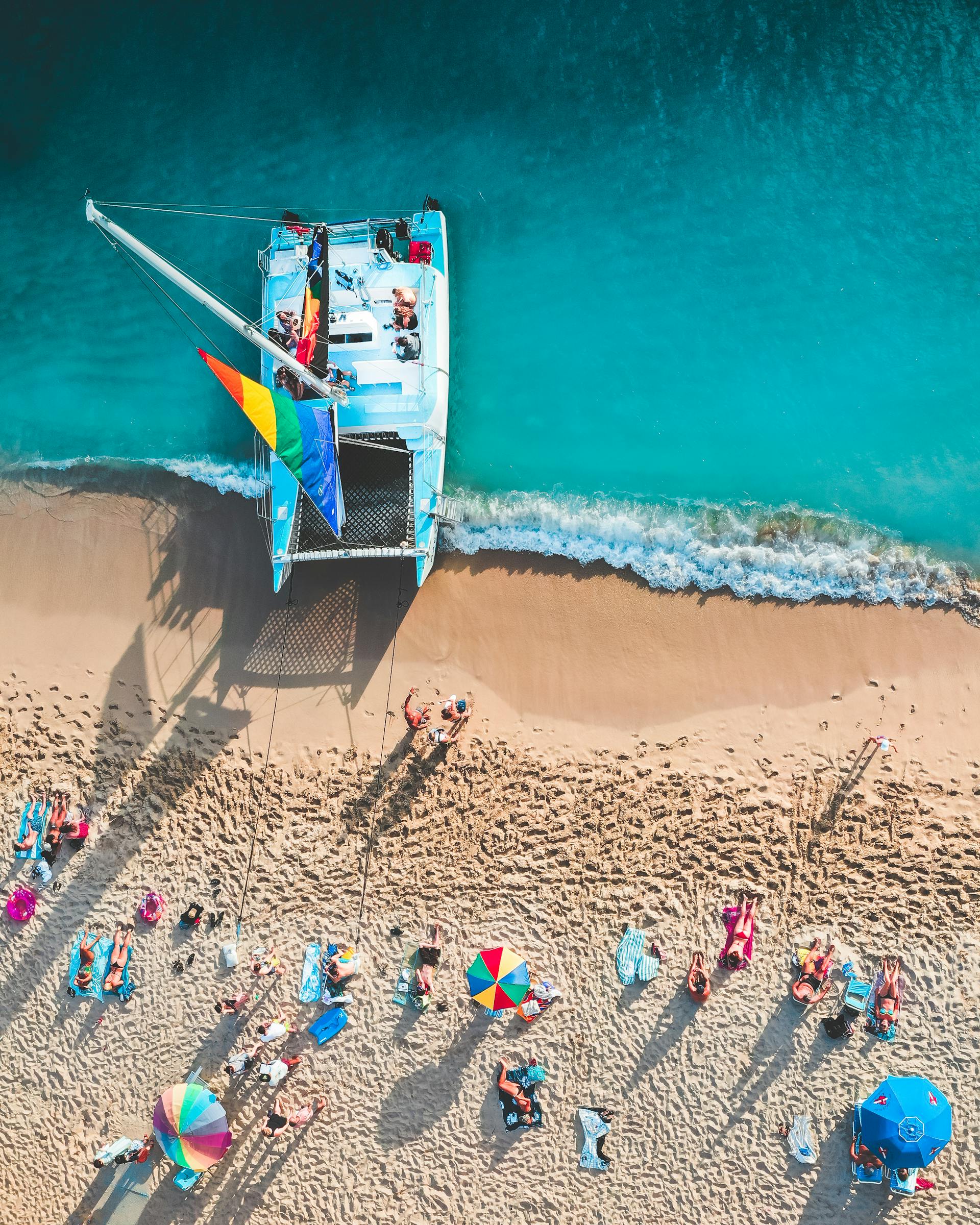 Aerial shot of a Hawaii beach with a catamaran — LGBTQ+ ocean and river cruises
