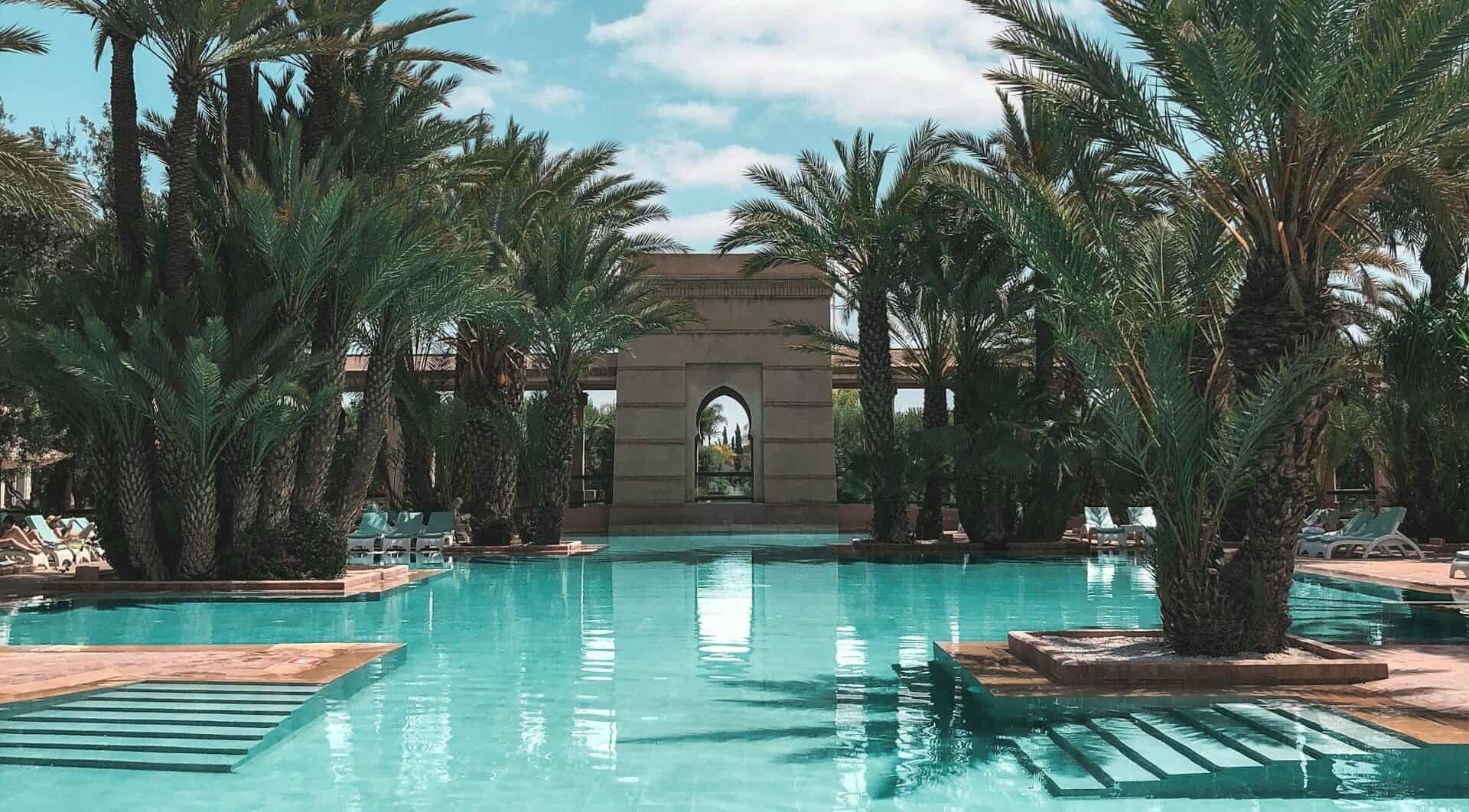 Luxury hotel pool with palm trees and elegant architecture at a desert resort.