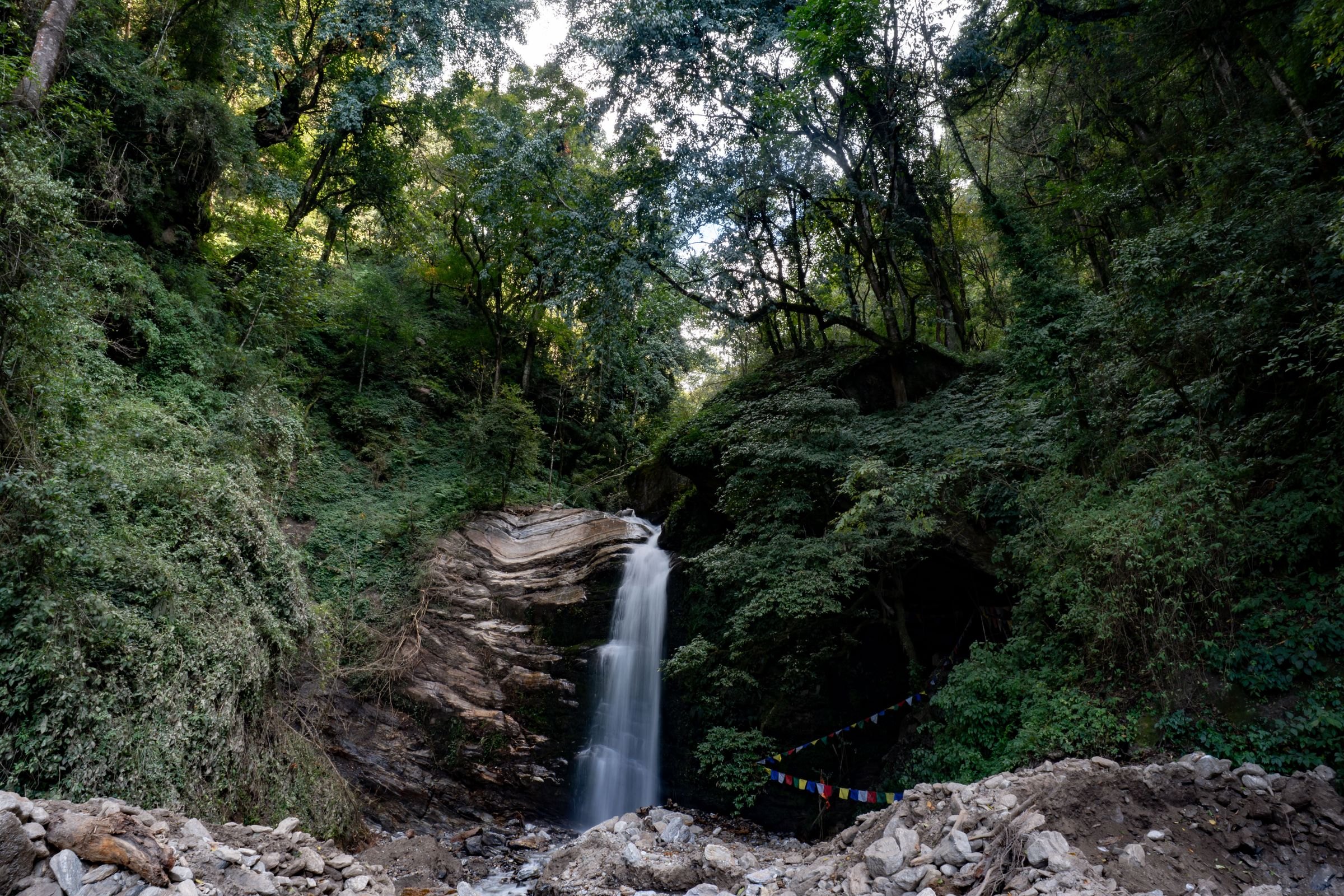 A waterfall and prayer flags in a Bhutan forest