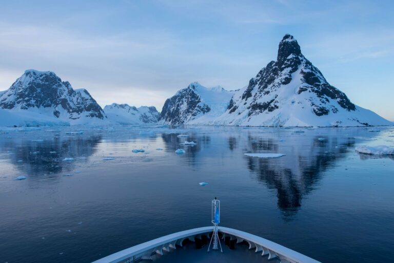 Snowy peaks reflected ahead of a ship's bow