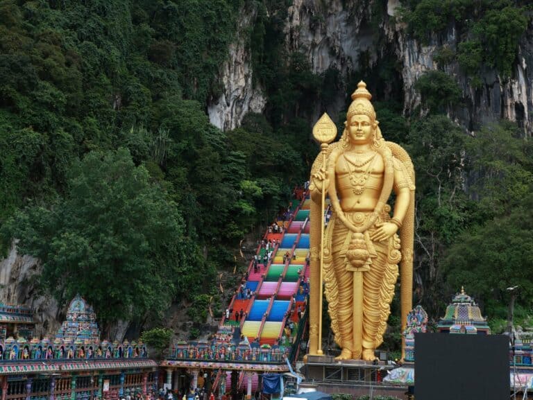 The golden Lord Murugan statue and rainbow steps at the Batu Caves, Malaysia