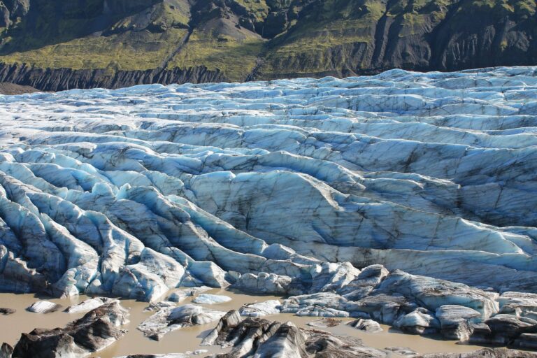 A blue glacier below rugged mountains
