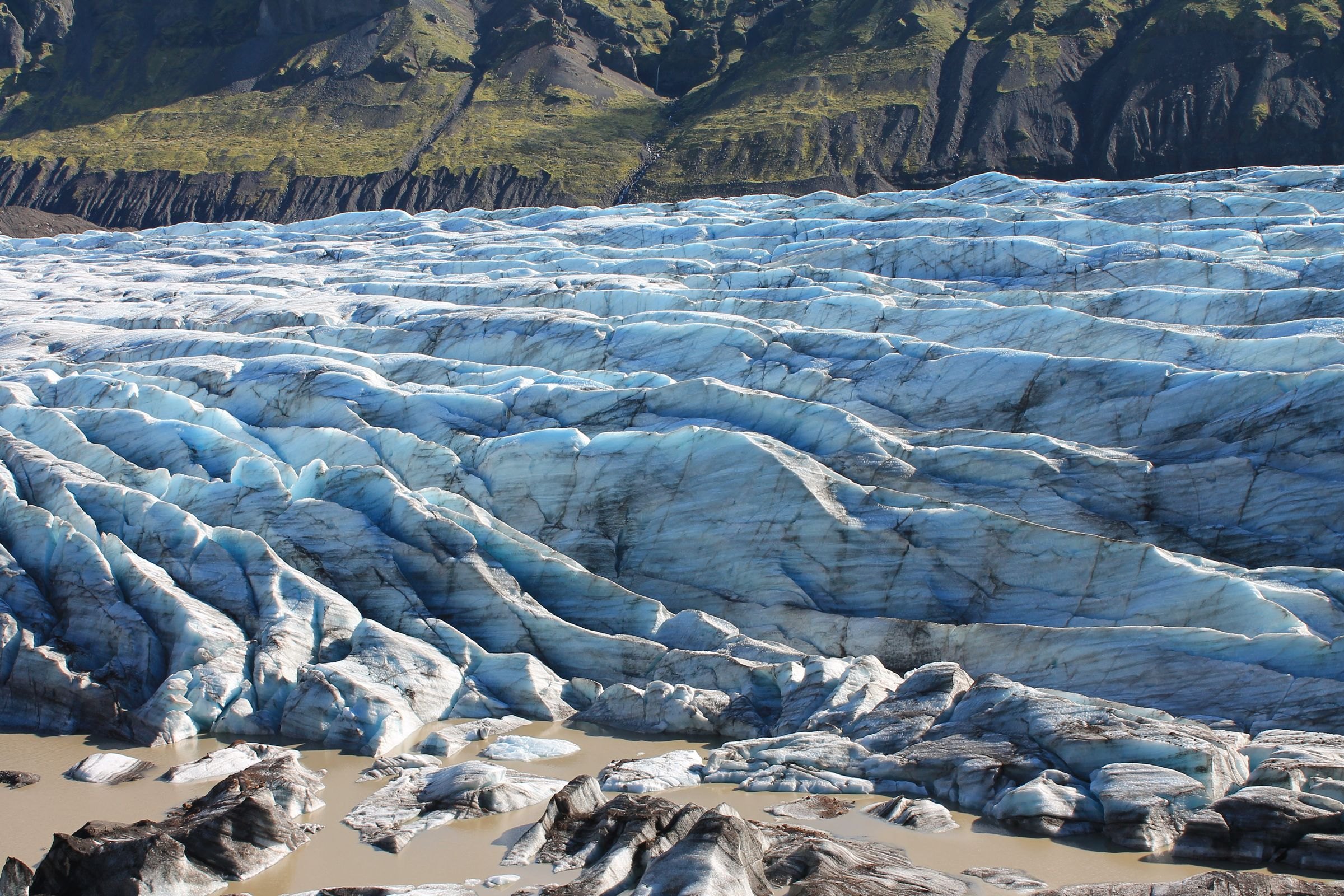 A blue glacier below rugged mountains