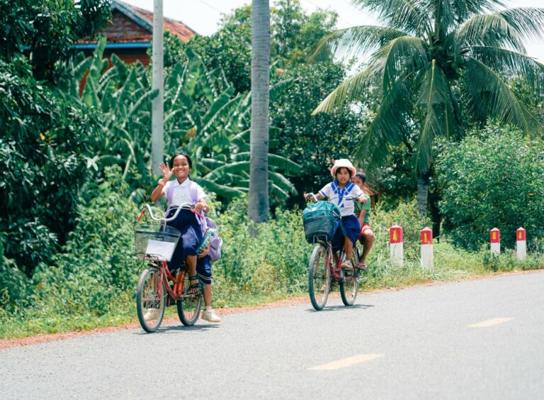 Children cycling on a rural road in Cambodia