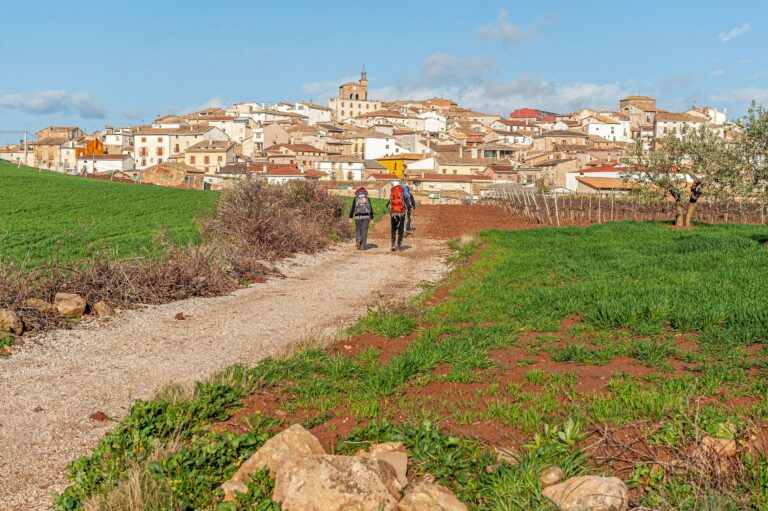 Two pilgrims walking towards a village on the Camino de Santiago