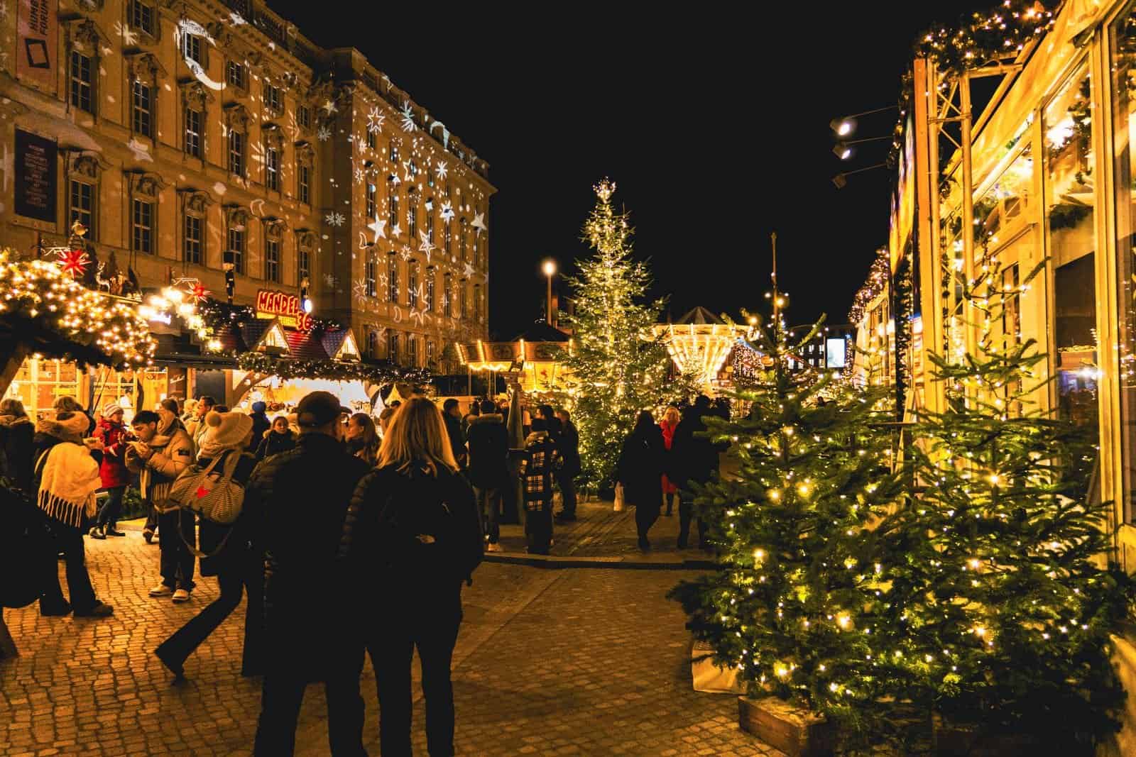 A Christmas market at night with lit stalls and trees
