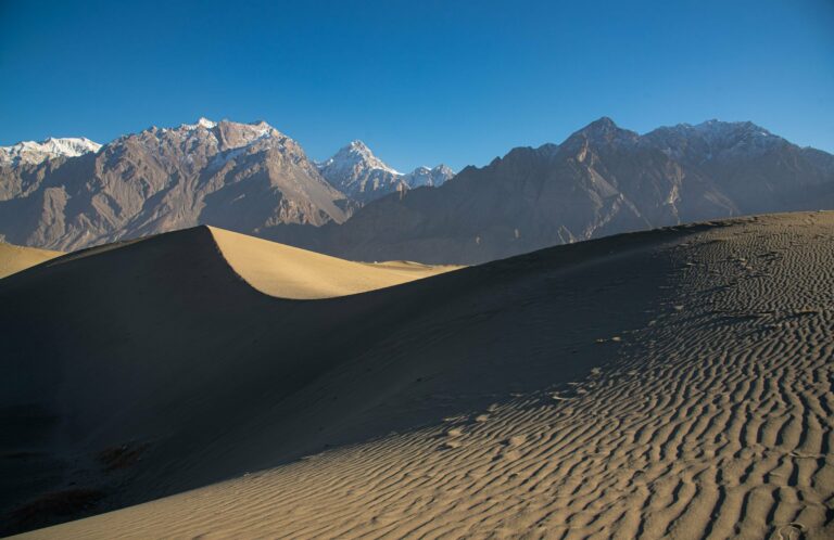 Sand dunes beneath snow-capped peaks near Skardu