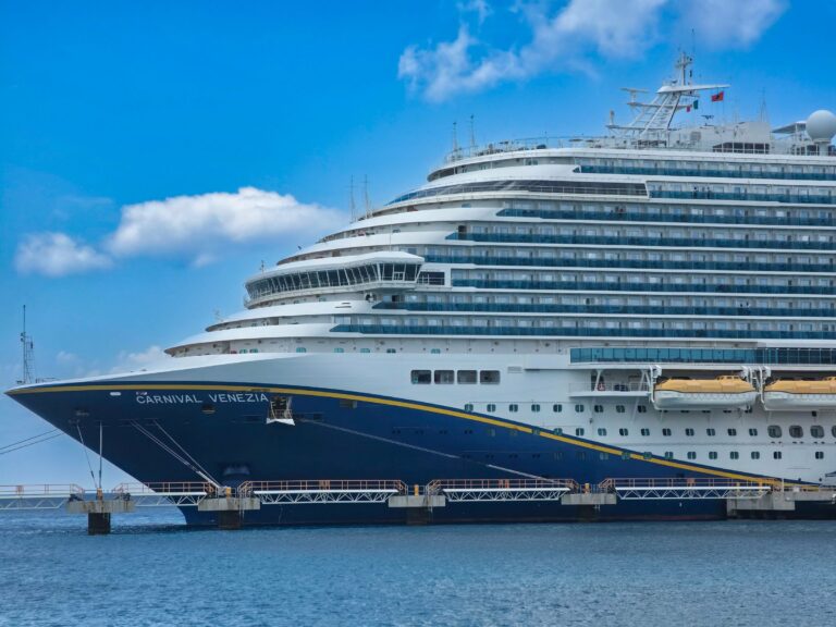 A large cruise ship docked under a blue sky