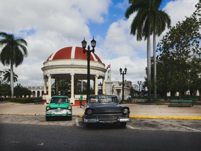 Classic cars by a pavilion in a Cuban plaza