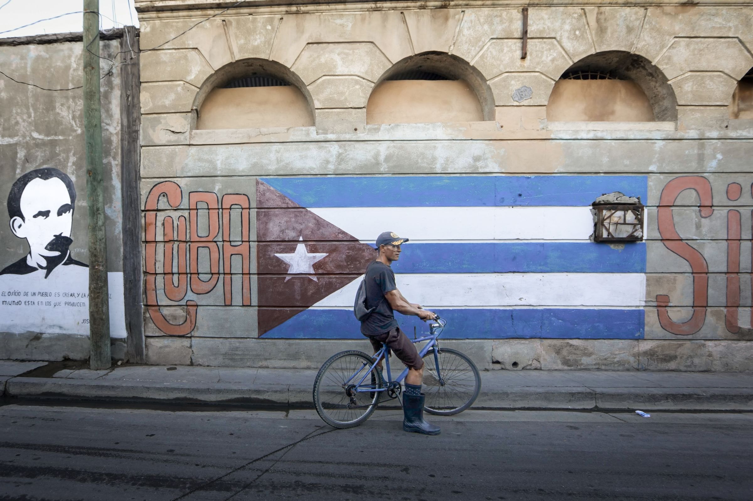 A cyclist passing a mural of the Cuban flag
