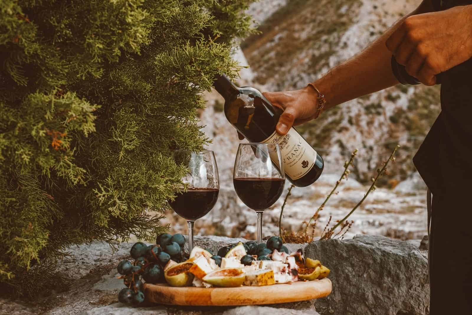 Red wine, cheese and grapes laid out on a stone table outdoors