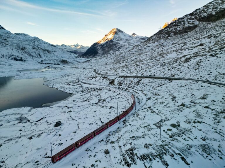 A red train crossing the snowy Swiss Alps