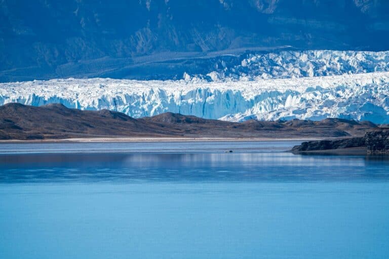 A glacier with icy cliffs meeting a fjord