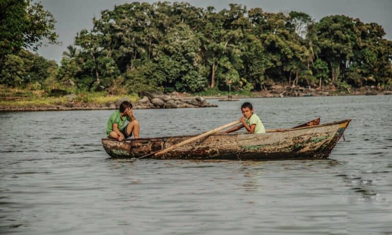 Two boys paddling a wooden boat near Granada, Nicaragua