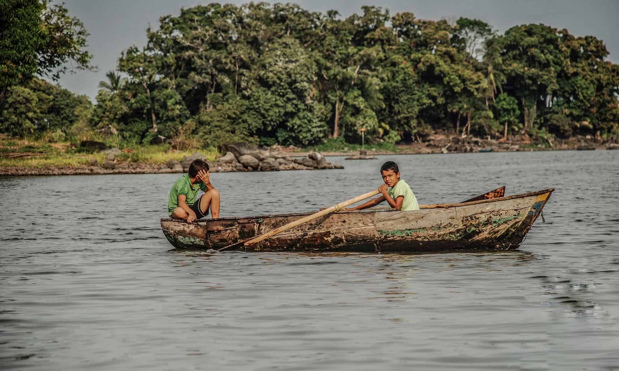 Two boys paddling a wooden boat near Granada, Nicaragua