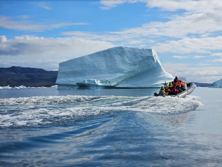 A boat beside a giant iceberg in Greenland