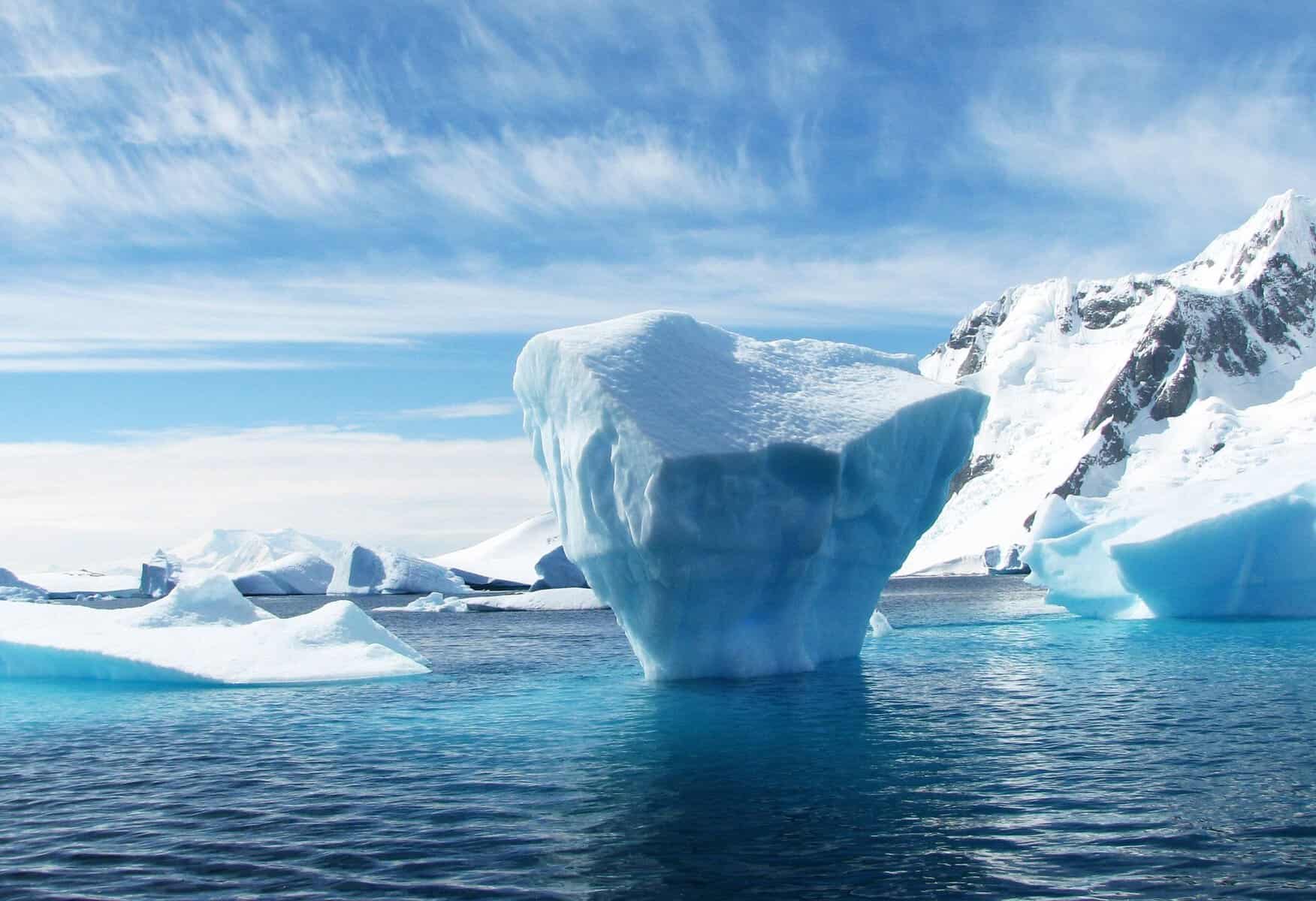 An iceberg floating beneath snowy mountains