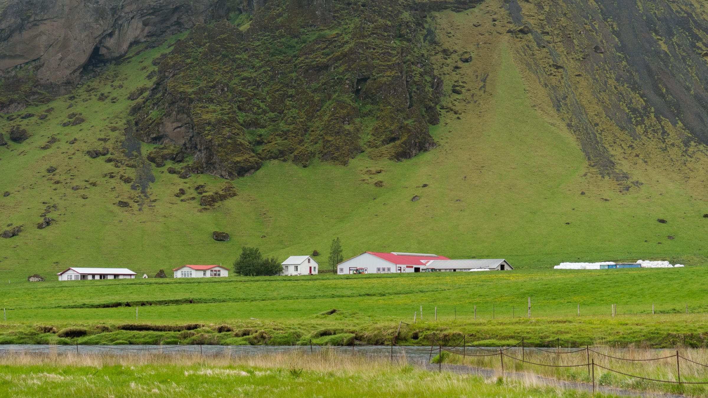 A farm below a green mountain in Iceland