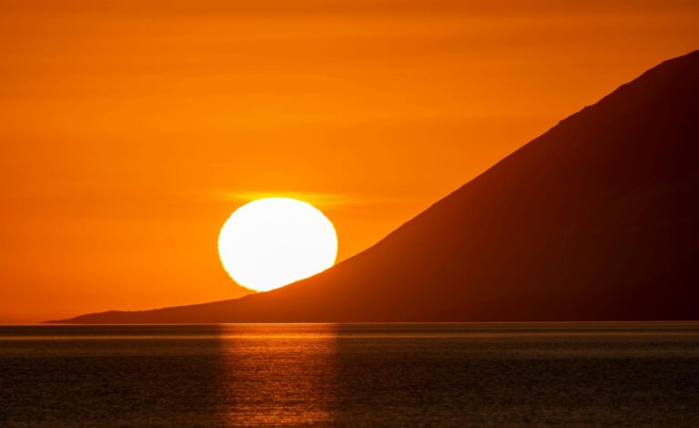 The sun low over the sea and mountains in an Icelandic summer