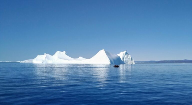 A small boat beside an iceberg at Ilulissat