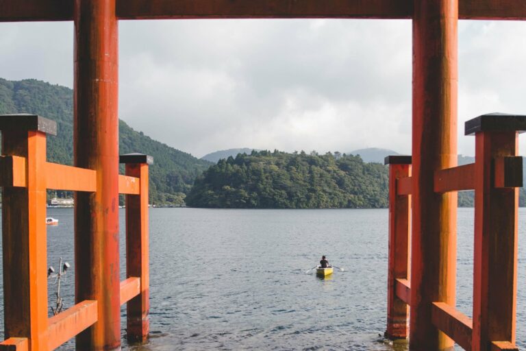 A kayaker on a lake beneath a torii gate