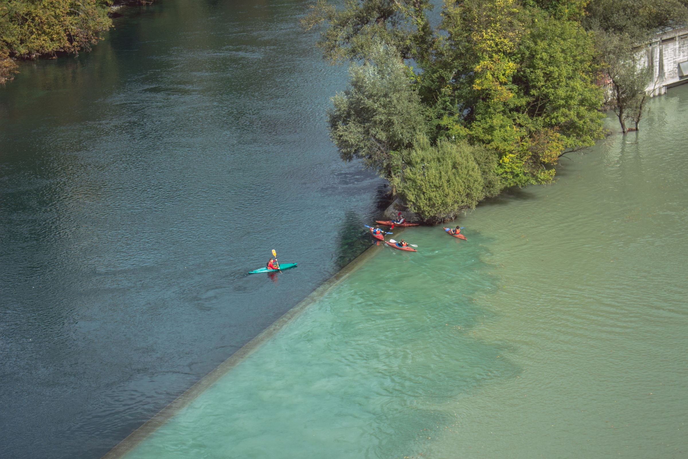 Kayakers on a green river from above