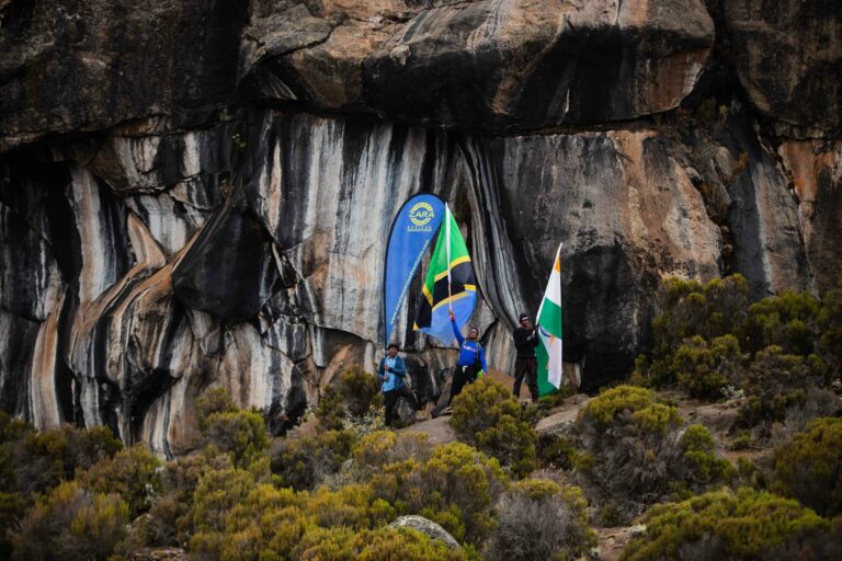 Hikers with flags at a cave on Kilimanjaro