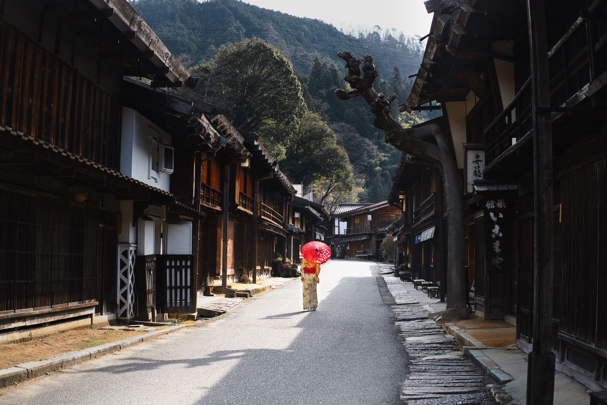 A woman with a red umbrella in a Kiso Valley post town