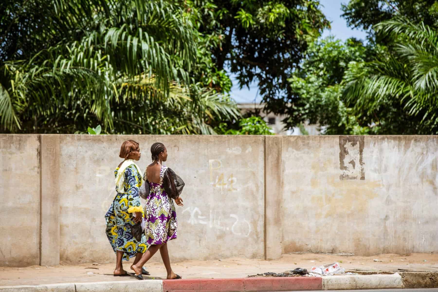 Women in colourful dresses walking along a street in Lomé, Togo