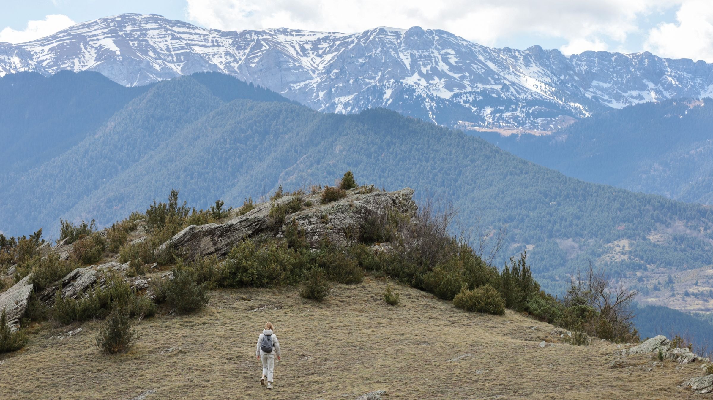 A hiker below snow-capped peaks