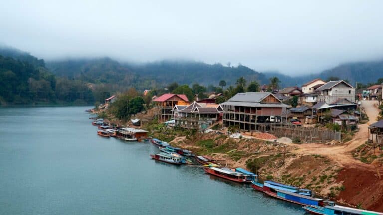 Boats on a river beneath misty mountains in northern Laos