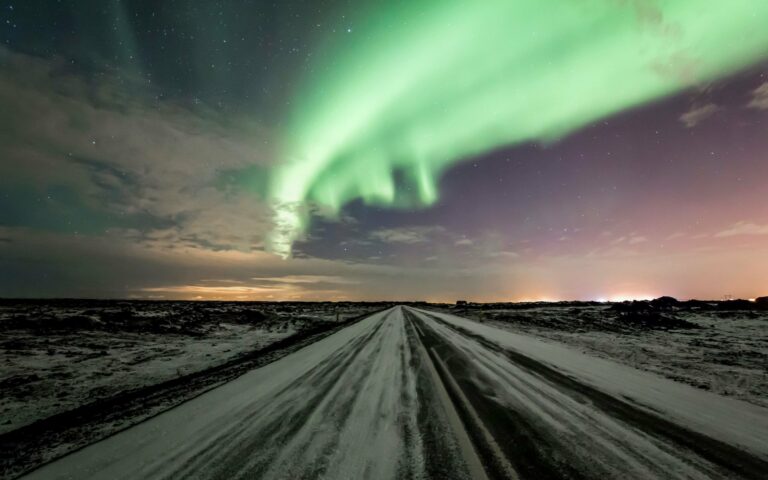 The Northern Lights over a snowy road in Iceland