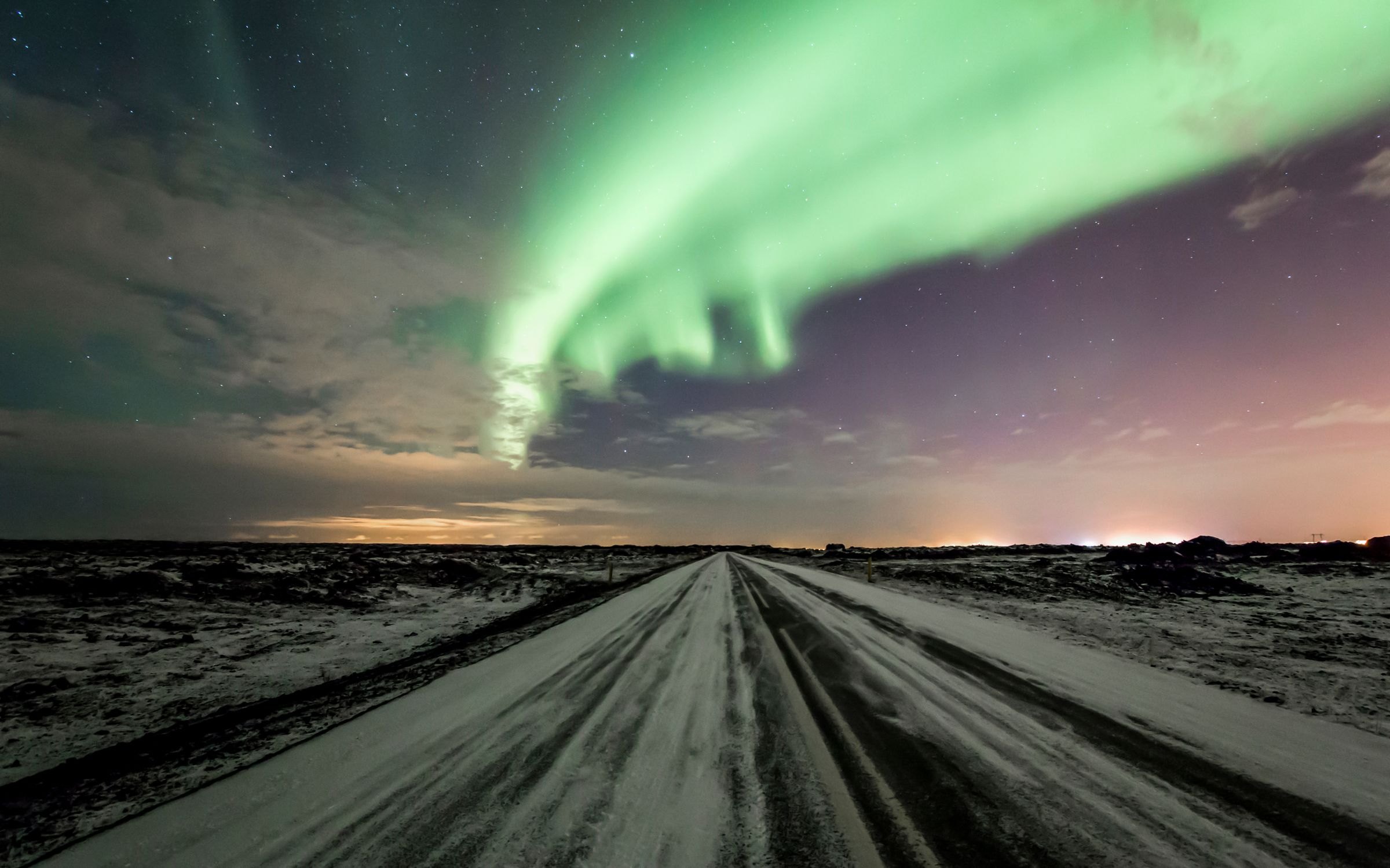 The Northern Lights over a snowy road in Iceland