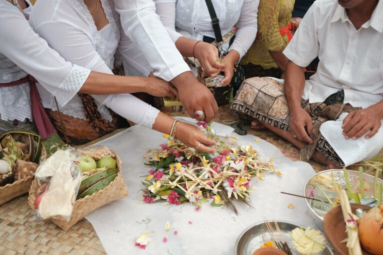 Hands arranging Balinese flower offerings