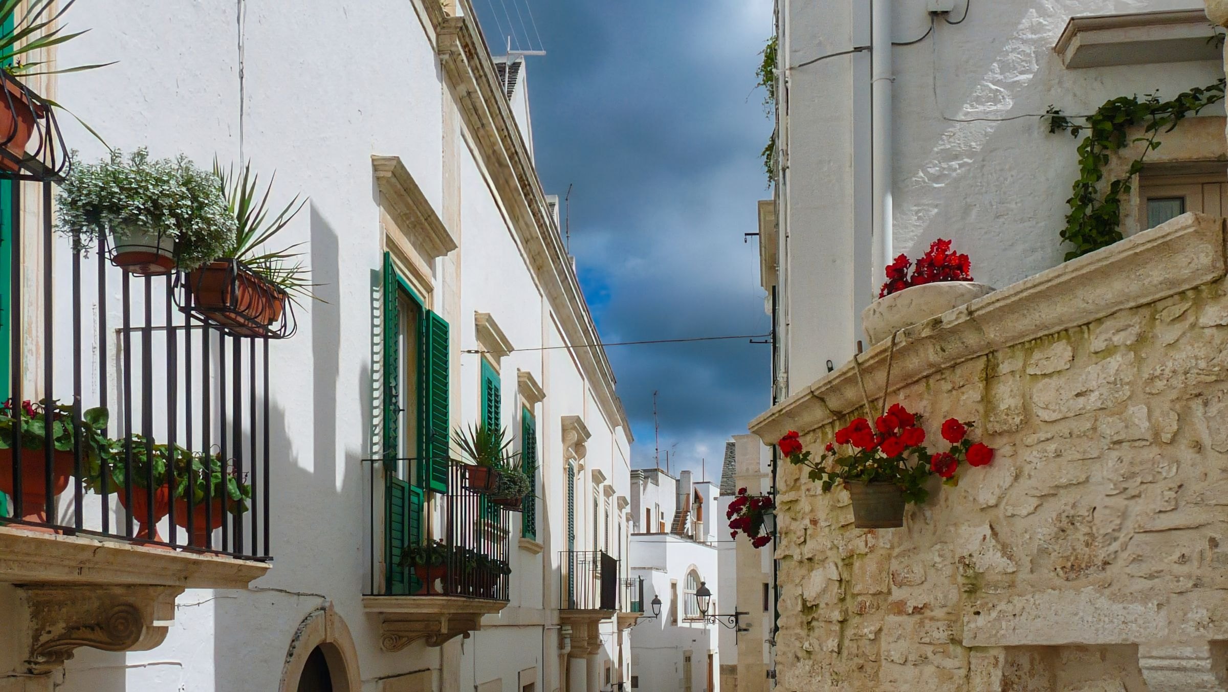 Flowered balconies on a white street in Ostuni