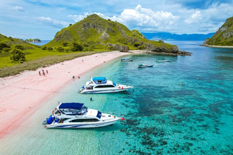 Boats off a pink sand beach in Komodo