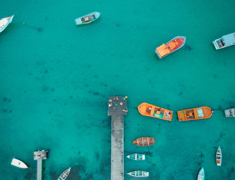 Boats moored in turquoise water by a jetty