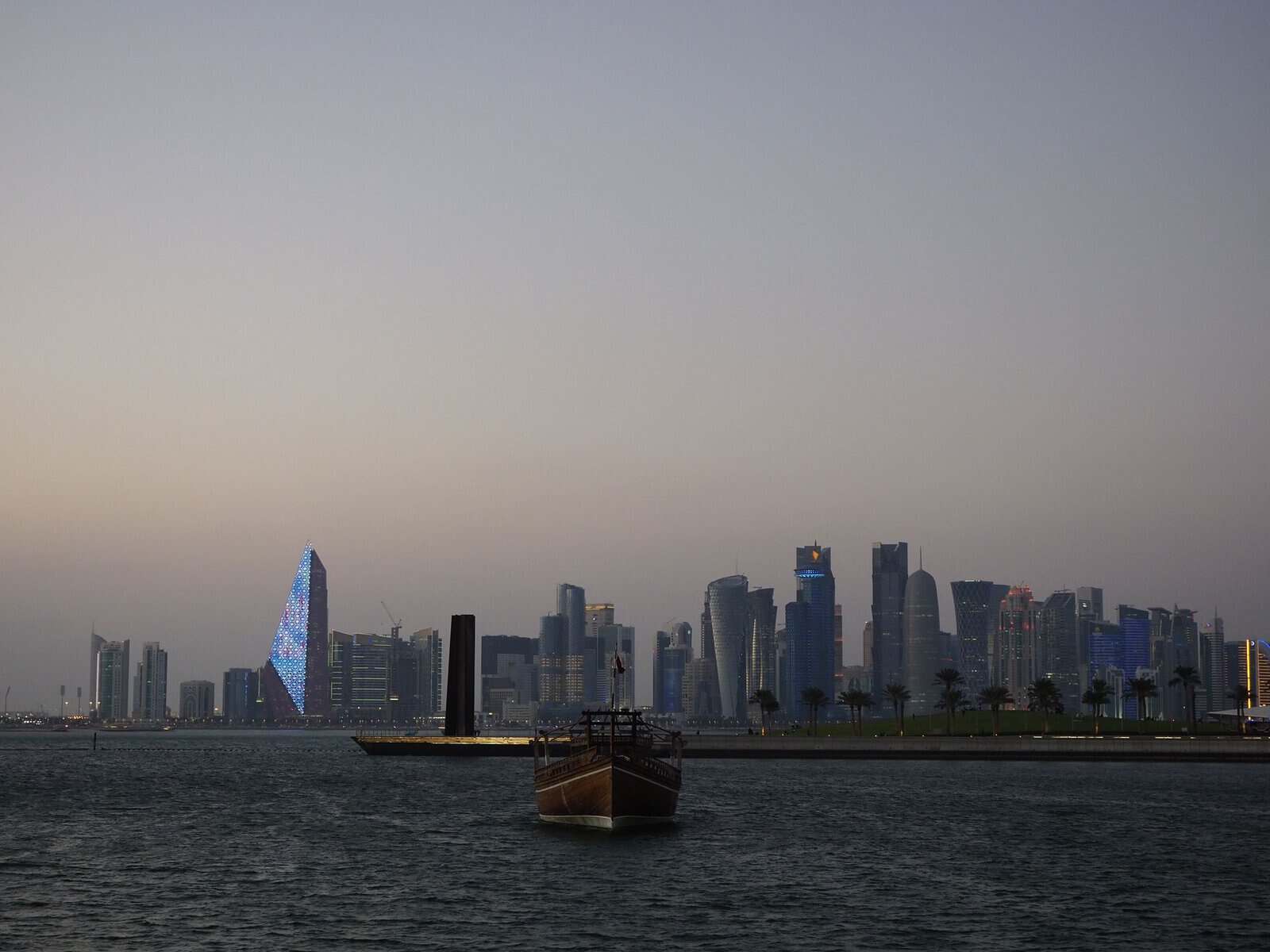 A traditional dhow in front of the Doha skyline at dusk, Qatar