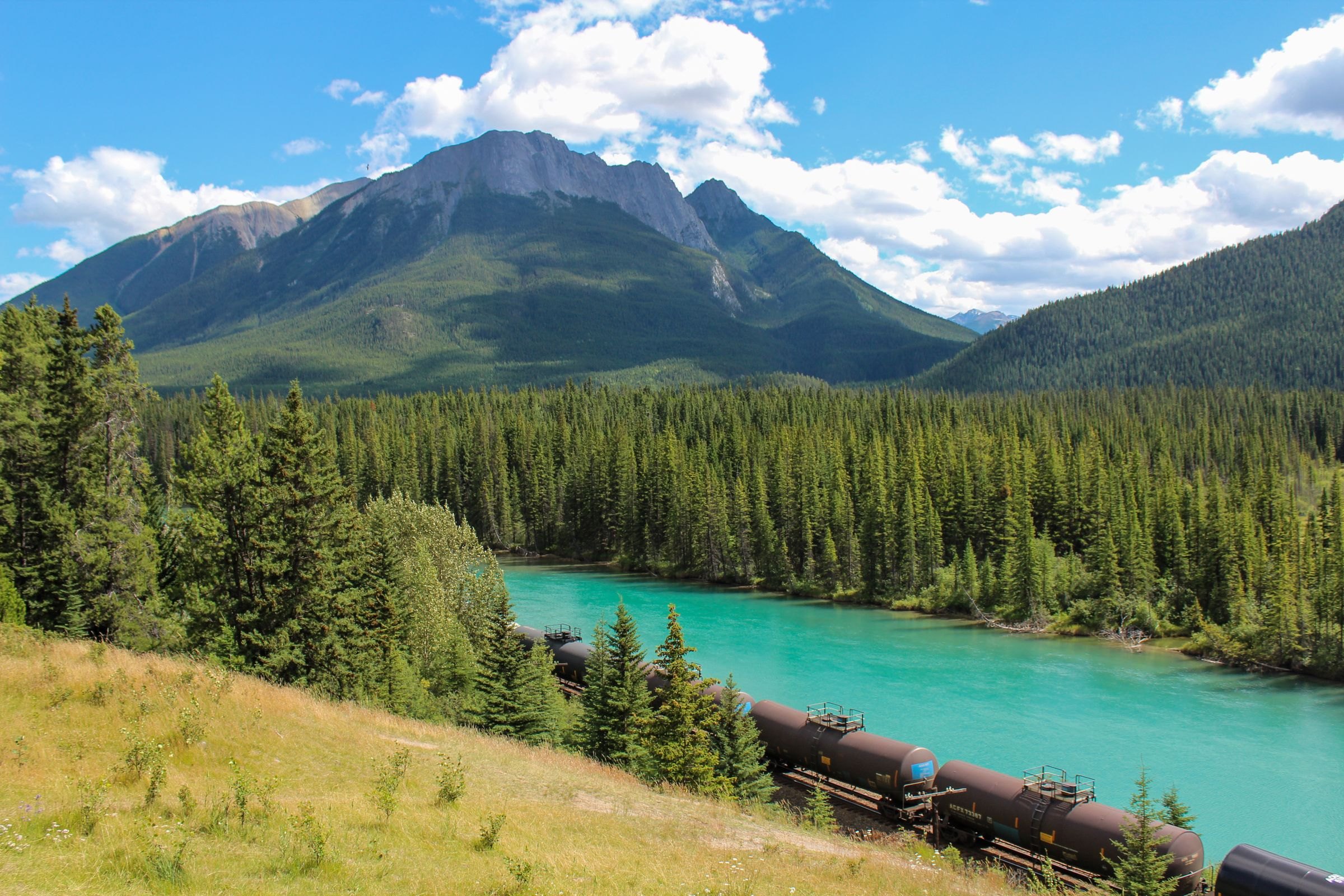 A train beside a turquoise river in the Rockies