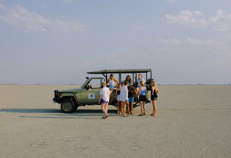 Travellers beside a safari vehicle on a salt pan