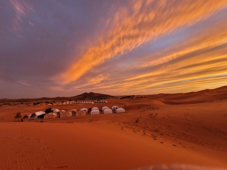White tents of a Sahara desert camp at sunset