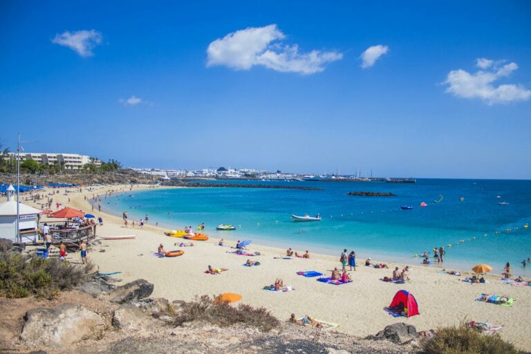 People enjoying Playa Blanca beach in Lanzarote with clear blue waters, Canary Islands