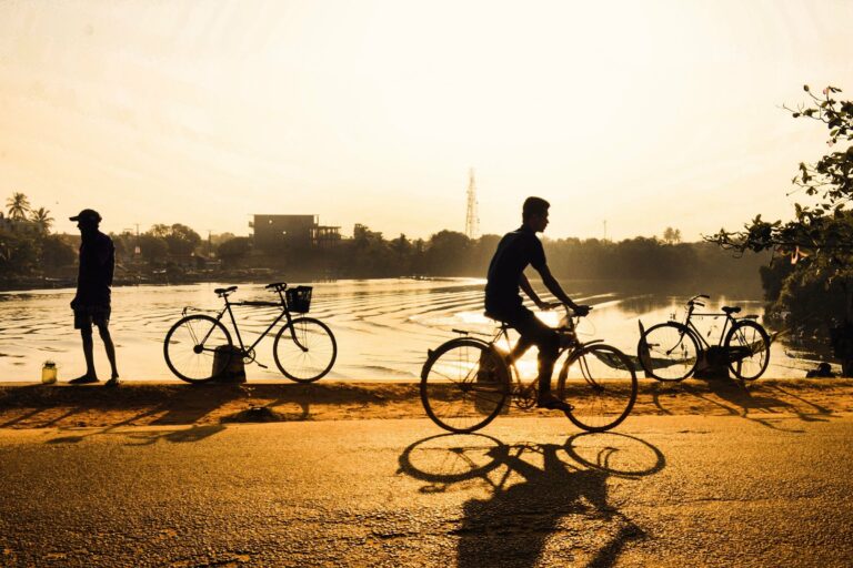 Cyclists by a lake at sunrise in Sri Lanka