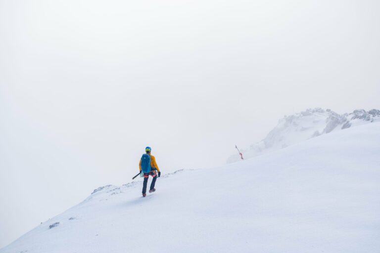 A climber on a snowy summit ridge