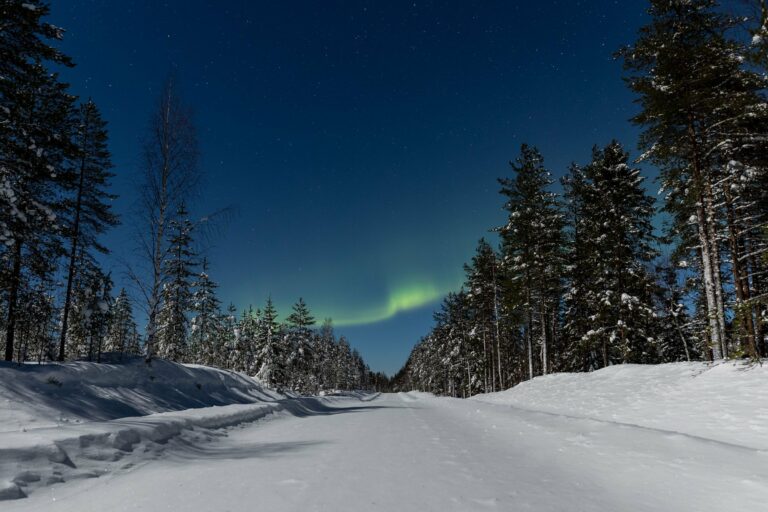 The Northern Lights over a snowy road in Finland