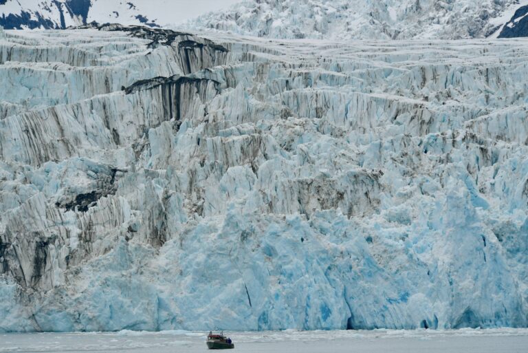 A small boat below a tidewater glacier