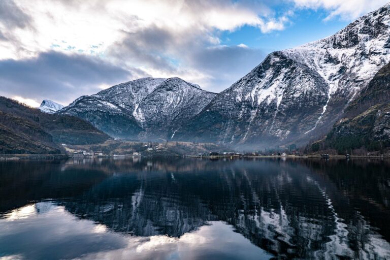 Snow-capped mountains reflected in a fjord in Vestland