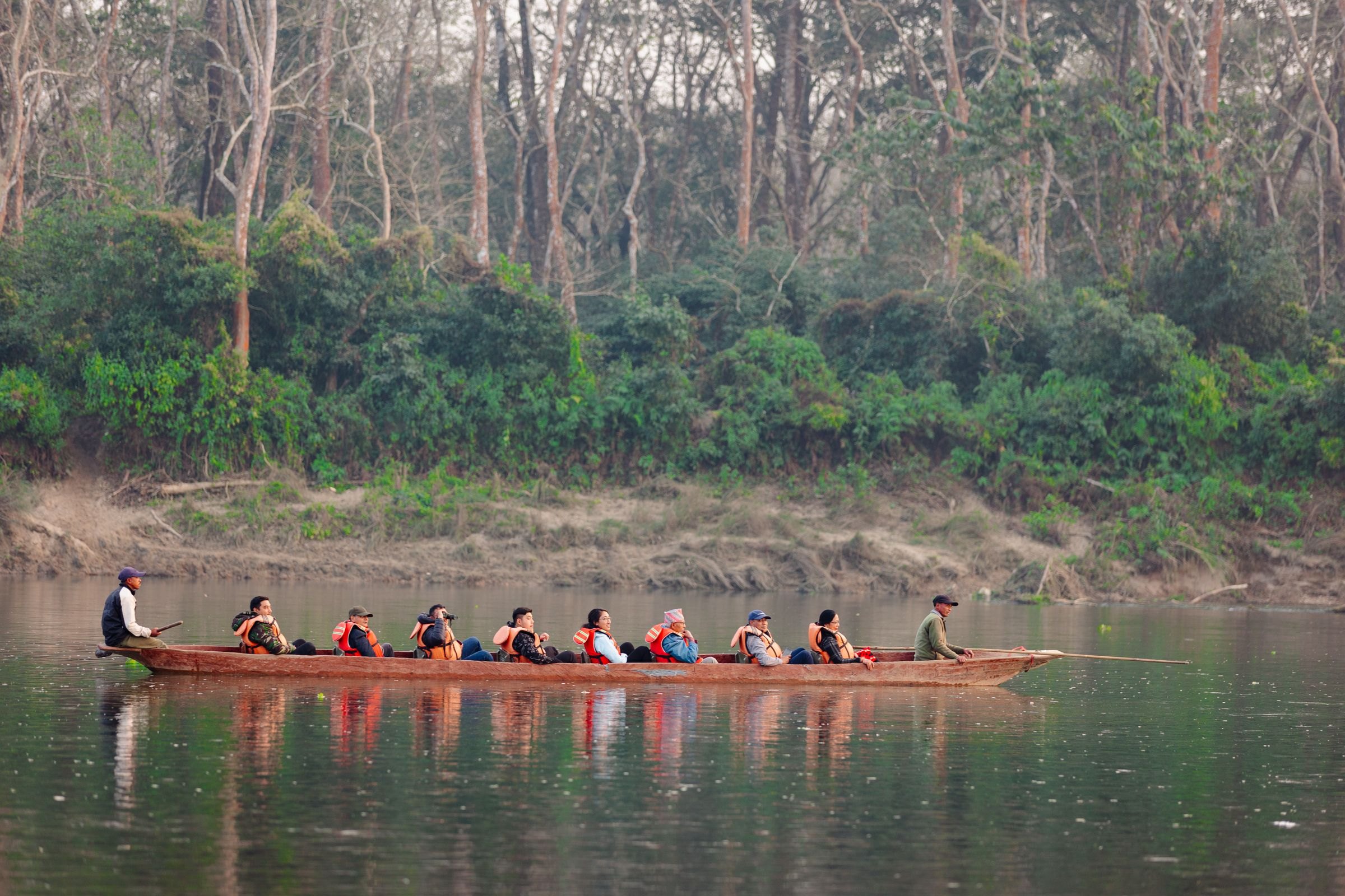 Visitors in a wooden canoe on a forest river in Chitwan